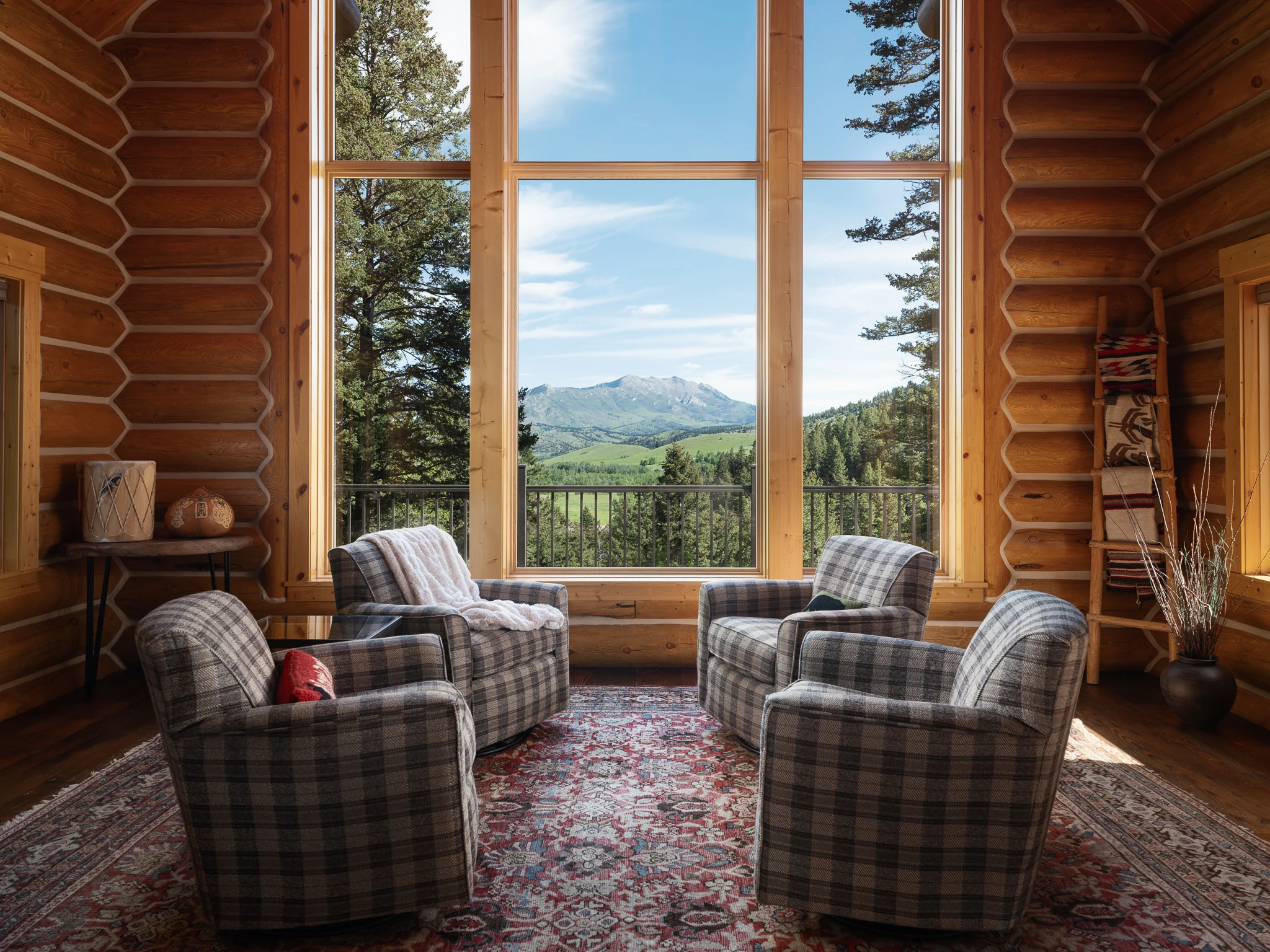 Living room with plaid armchairs framed by floor-to-ceiling windows onto the mountains — architectural photography Livingston Montana, Sam Schlauch Designs